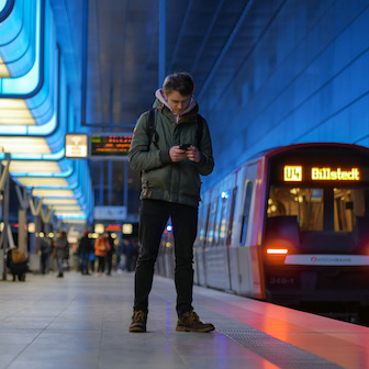 Ein junger Mann (ich) steht am Bahnsteig der U-Bahn und blickt auf sein Handy